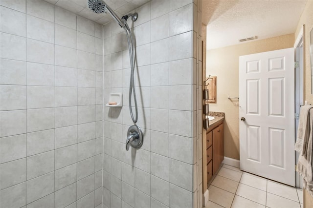 bathroom with vanity, tile patterned flooring, a textured ceiling, and a tile shower