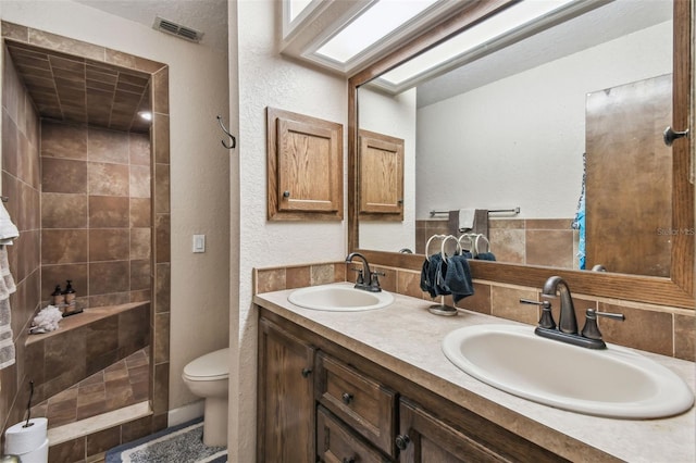 bathroom with vanity, toilet, and a tile shower