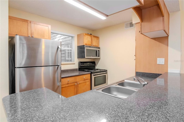 kitchen featuring stainless steel appliances, sink, light brown cabinets, and kitchen peninsula