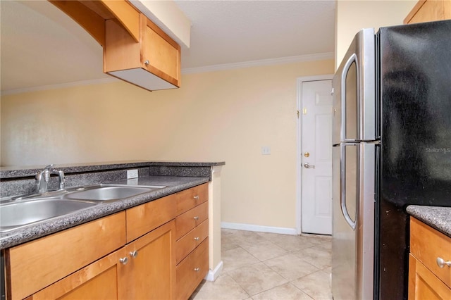 kitchen featuring crown molding, sink, light tile patterned flooring, and stainless steel fridge