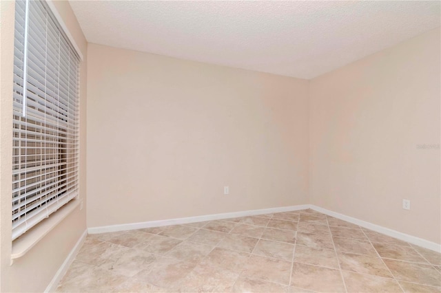 tiled empty room with a textured ceiling