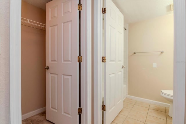 bathroom featuring tile patterned floors, a tub, and toilet