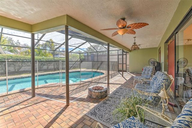 view of swimming pool with ceiling fan, a lanai, a fire pit, and a patio area