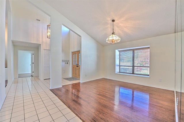 unfurnished room featuring high vaulted ceiling, a chandelier, and light hardwood / wood-style flooring