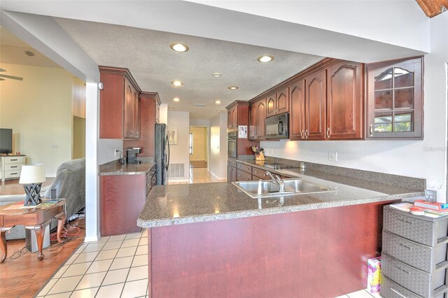 kitchen with black appliances, sink, light tile patterned floors, kitchen peninsula, and a textured ceiling