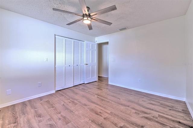 unfurnished bedroom with ceiling fan, light hardwood / wood-style flooring, a closet, and a textured ceiling