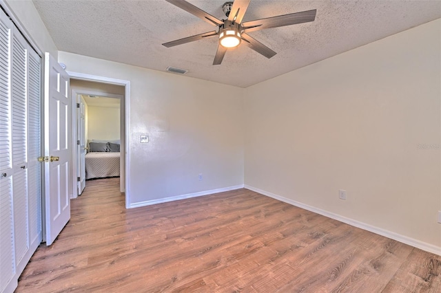 unfurnished bedroom featuring hardwood / wood-style flooring, a closet, ceiling fan, and a textured ceiling