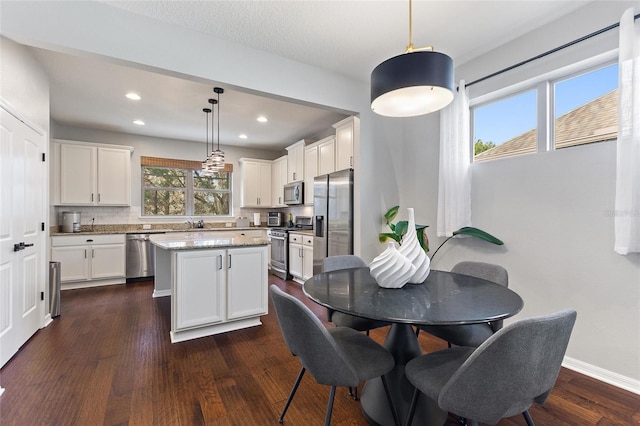 kitchen featuring decorative light fixtures, tasteful backsplash, a center island, light stone counters, and stainless steel appliances