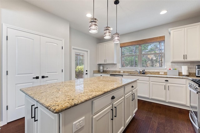 kitchen featuring light stone countertops, white cabinetry, a kitchen island, and decorative light fixtures