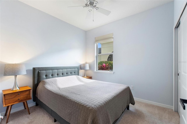 bedroom with ceiling fan, light colored carpet, and a closet