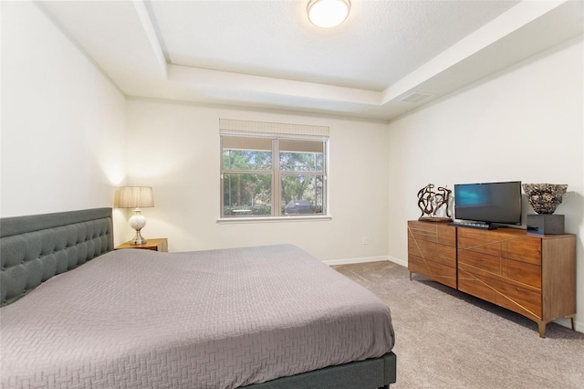 bedroom featuring light colored carpet and a tray ceiling