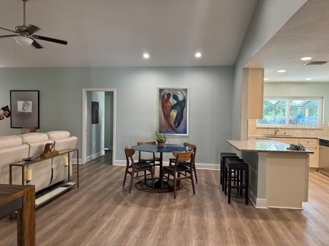 dining area featuring hardwood / wood-style flooring, vaulted ceiling, sink, and ceiling fan