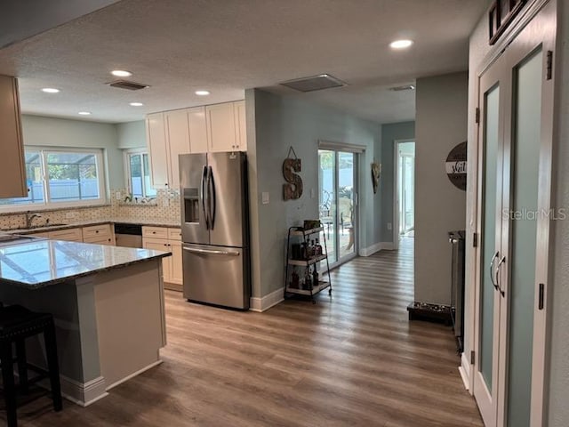 kitchen with a breakfast bar, white cabinetry, light hardwood / wood-style flooring, appliances with stainless steel finishes, and kitchen peninsula