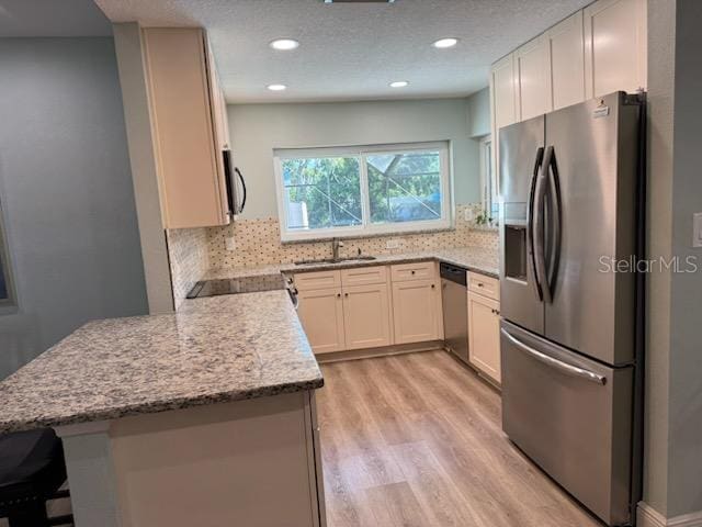 kitchen featuring white cabinetry, backsplash, light stone counters, kitchen peninsula, and stainless steel appliances