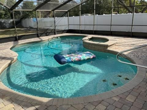 view of swimming pool with an in ground hot tub, a lanai, and a patio