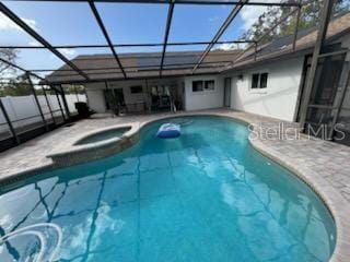 view of swimming pool with an in ground hot tub, glass enclosure, and a patio