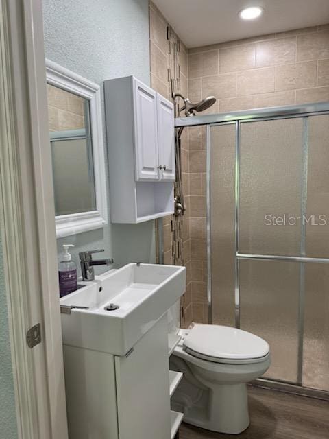 bathroom featuring walk in shower, vanity, toilet, and hardwood / wood-style floors