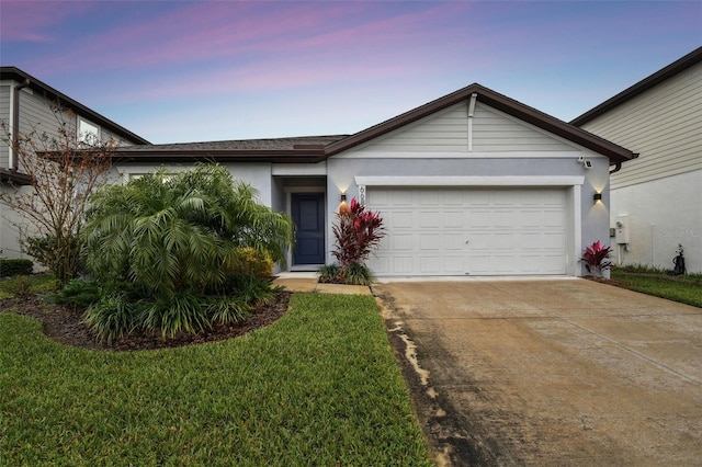 ranch-style home with a garage and a lawn