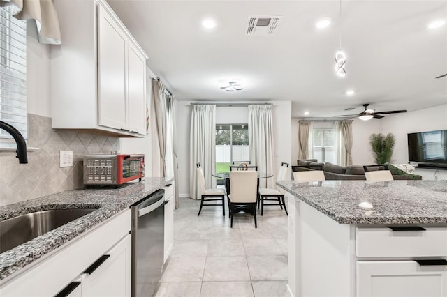 kitchen featuring tasteful backsplash, dishwasher, sink, white cabinets, and light tile patterned floors