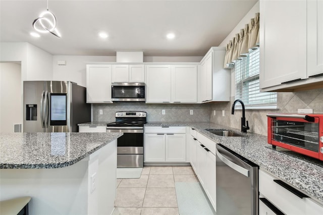 kitchen featuring sink, white cabinetry, hanging light fixtures, stone counters, and stainless steel appliances