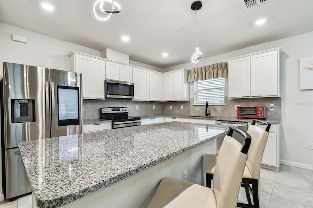 kitchen featuring white cabinetry, hanging light fixtures, a kitchen island, and appliances with stainless steel finishes