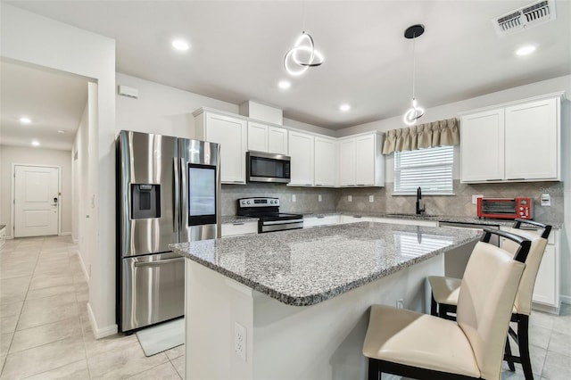 kitchen featuring stainless steel appliances, white cabinetry, and a center island