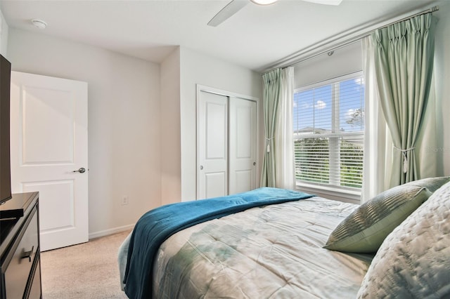 bedroom featuring light colored carpet, ceiling fan, and a closet