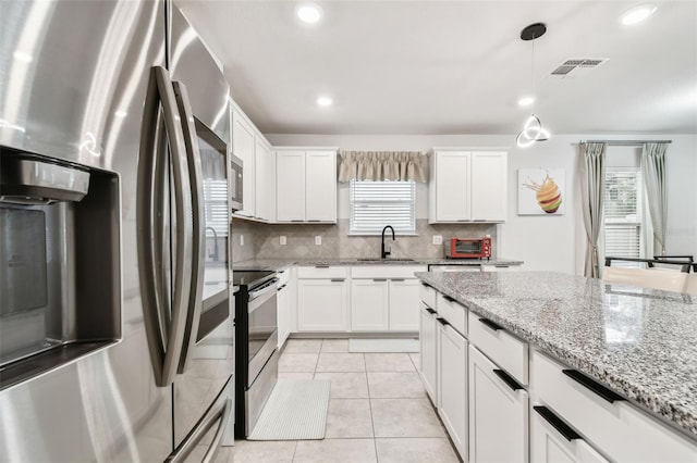 6684 Devlin Ln, Wesley Chapel, FL 33545 - kitchen with stainless steel appliances, a healthy amount of sunlight, visible vents, backsplash, and white cabinetry