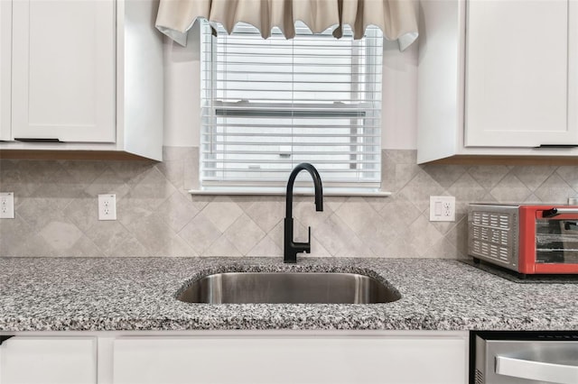 6684 Devlin Ln, Wesley Chapel, FL 33545 - kitchen featuring white cabinets, backsplash, light stone countertops, and a sink