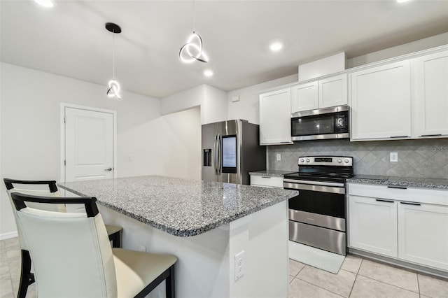 6684 Devlin Ln, Wesley Chapel, FL 33545 - kitchen featuring decorative backsplash, light tile patterned floors, stainless steel appliances, white cabinets, and a kitchen island