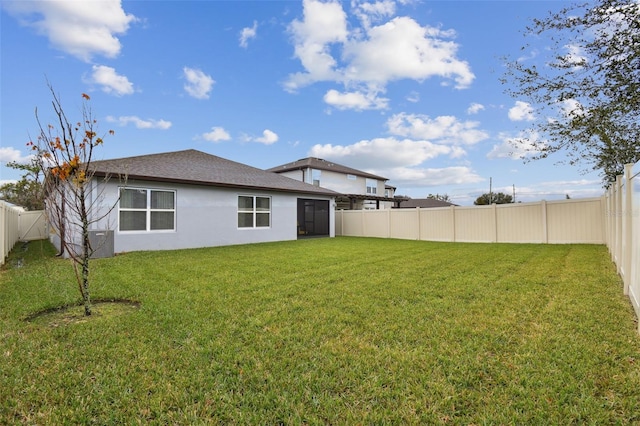 6684 Devlin Ln, Wesley Chapel, FL 33545 - back of house with a fenced backyard, roof with shingles, a yard, and stucco siding