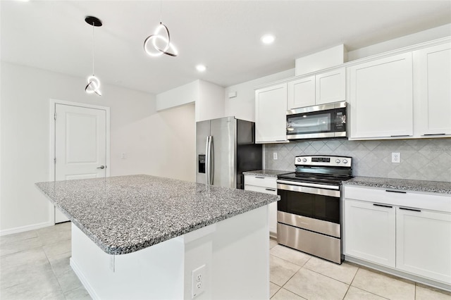 6684 Devlin Ln, Wesley Chapel, FL 33545 - kitchen with appliances with stainless steel finishes, light tile patterned flooring, decorative backsplash, a center island, and white cabinetry