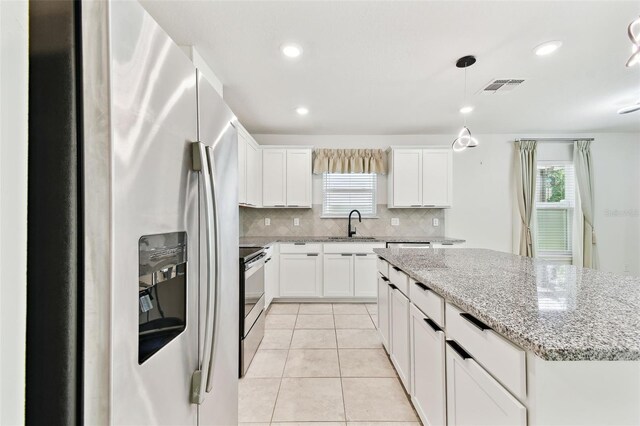 6684 Devlin Ln, Wesley Chapel, FL 33545 - kitchen featuring appliances with stainless steel finishes, tasteful backsplash, white cabinetry, plenty of natural light, and recessed lighting