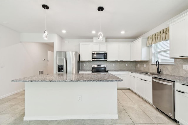 6684 Devlin Ln, Wesley Chapel, FL 33545 - kitchen with appliances with stainless steel finishes, a kitchen island, tasteful backsplash, light stone counters, and recessed lighting