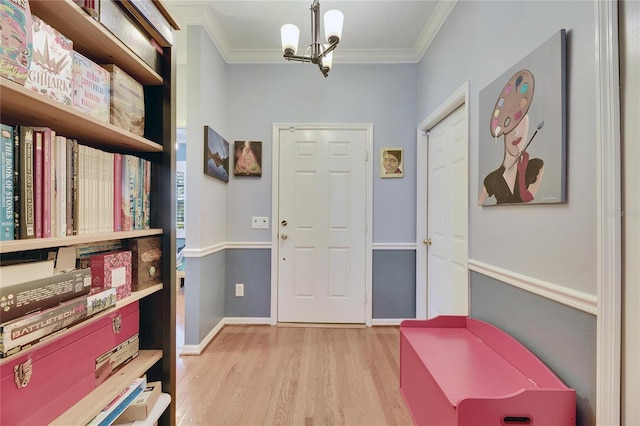 entrance foyer featuring crown molding, a notable chandelier, and light wood-type flooring