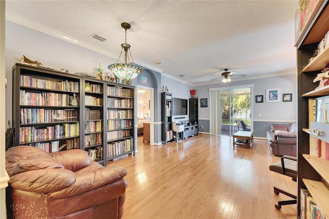 interior space featuring ceiling fan, crown molding, a textured ceiling, and light wood-type flooring