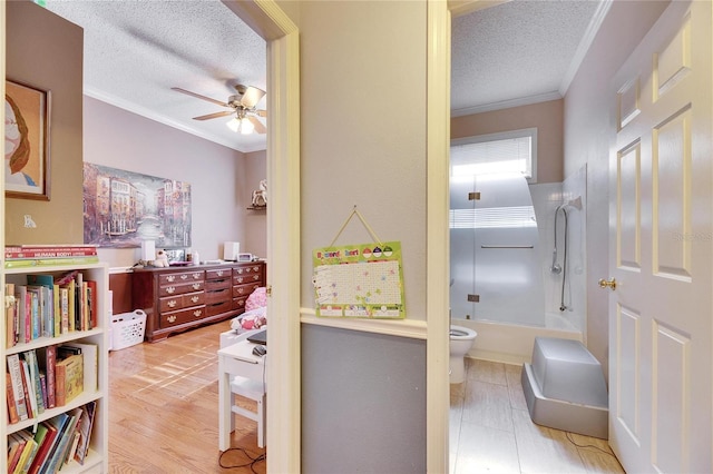 bedroom with crown molding, light hardwood / wood-style flooring, ensuite bath, and a textured ceiling