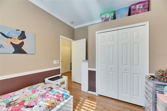 bedroom with a closet, crown molding, a textured ceiling, and light hardwood / wood-style flooring