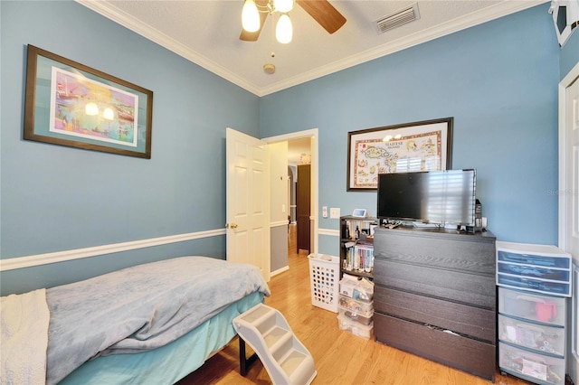 bedroom featuring ceiling fan, ornamental molding, and light hardwood / wood-style flooring