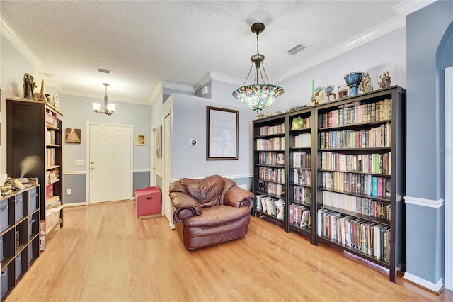 sitting room with ornamental molding, a textured ceiling, and light wood-type flooring