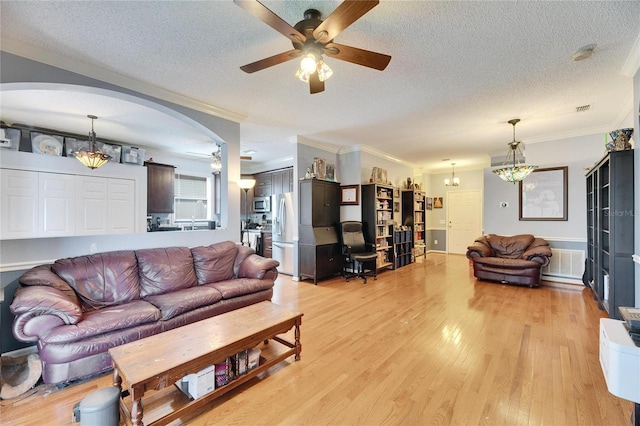 living room featuring ornamental molding, a textured ceiling, and light wood-type flooring