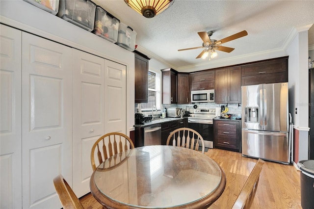 kitchen featuring dark brown cabinetry, sink, crown molding, light hardwood / wood-style flooring, and appliances with stainless steel finishes