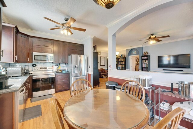 kitchen with crown molding, dark brown cabinets, light wood-type flooring, appliances with stainless steel finishes, and decorative backsplash