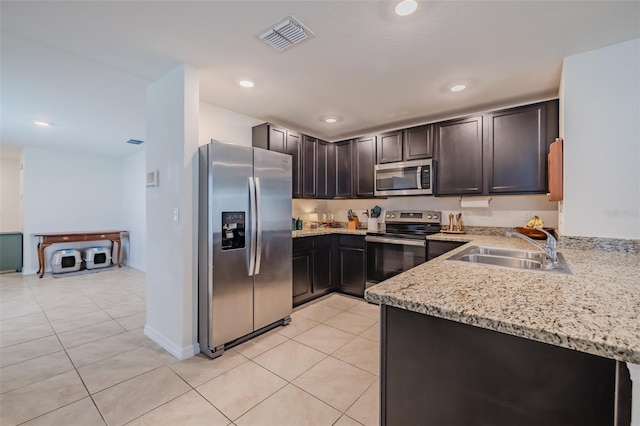 kitchen featuring sink, light tile patterned floors, light stone counters, stainless steel appliances, and dark brown cabinets