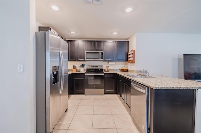 kitchen featuring sink, light stone counters, light tile patterned floors, appliances with stainless steel finishes, and kitchen peninsula