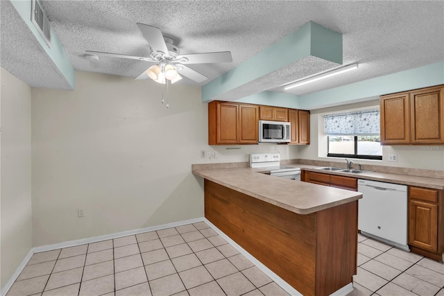 kitchen featuring sink, white appliances, light tile patterned floors, a textured ceiling, and kitchen peninsula