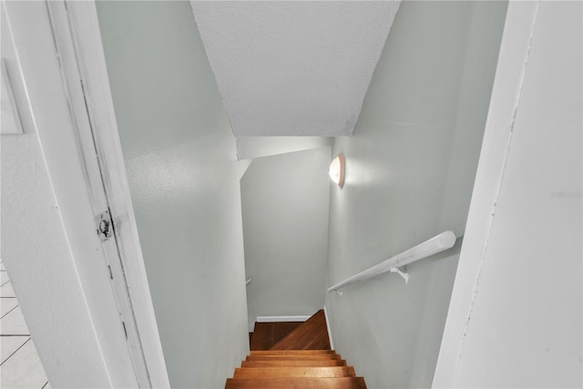 staircase with hardwood / wood-style floors and a textured ceiling