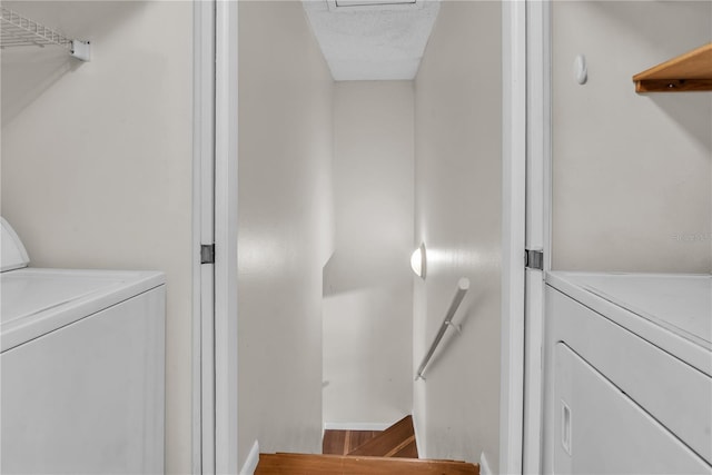 clothes washing area featuring hardwood / wood-style floors, washing machine and clothes dryer, and a textured ceiling