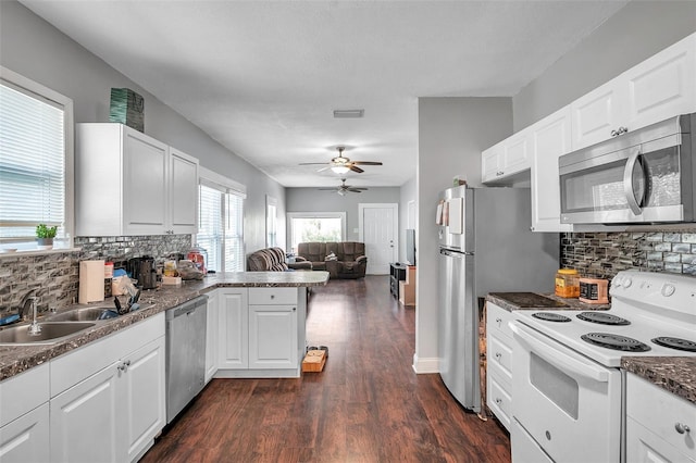 kitchen with tasteful backsplash, kitchen peninsula, white cabinets, and appliances with stainless steel finishes