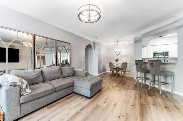 1203 Bay Club Cir Unit 1203, Tampa, FL 33607 - living area featuring a chandelier, arched walkways, light wood-style flooring, baseboards, and ornamental molding